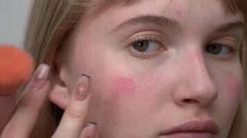 Woman uses finger to blend blush, and process of creating natural looking skin tone can be achieved by applying blush to face with makeup brush. extreme close-up view application process of cosmetics video