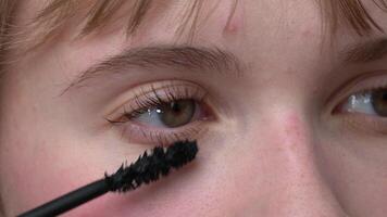Woman is shown in an extreme close-up applying mascara to her brown eyes with the tip of brush to prevent clumping. Mascara may enhance and define appearance of eyes. Extreme close-up view process video