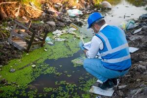 Water resource experts check the water quality in a community canal contaminated with garbage in the canal. photo