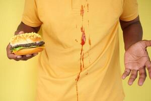 A yellow shirt was stained by spilled ketchup, requiring cleaning to remove the blot photo