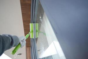 Rubber squeegee cleans a soaped window. photo