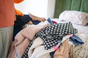 A Large Pile of Clothing Sitting on a Bed Awaiting Sorting and Organizing photo