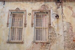 The weathered wall with secured windows stands out in an urban setting photo