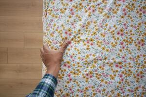 A gentle hand rests upon the colorful, floral patterned bedding, highlighting its soft design. photo