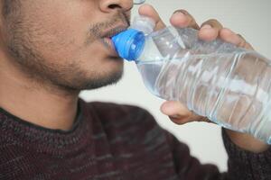 A CloseUp Image of an Individual Consuming Water Directly from a Bottle in a Casual Setting photo