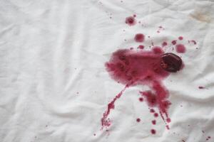 There is a spill of red wine on the white fabric, creating a noticeable stain photo