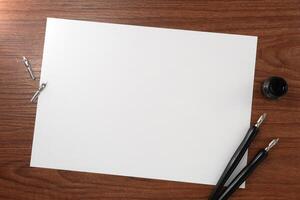 A paper with dip pen on wooden texture background. Writer workplace concept. photo