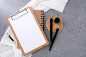Blank clipboard and dip pen on stone texture background. Writer workplace concept. photo