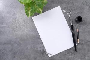 Blank paper with dip pen on stone texture background. Writer workplace concept. photo