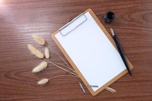 Clipboard and dip pen and dried grass on wooden texture background. photo