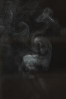 Ethereal and captivating smoke patterns emerge gracefully against a dark, rich background photo