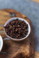 A closeup view of dried cloves beautifully arranged in a bowl set upon a wooden surface photo