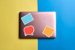 A closed laptop showing its cover is placed on a solid plain background and few blank sticker mockups are attached photo