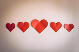Five different sizes red heart stickers are attached on a background wall representing mockup as well photo