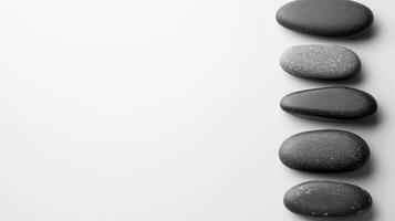 A serene line of black spa stones rests on a clean white background photo