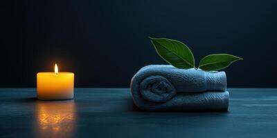 A serene spa setup featuring a white towel, glowing candle, and green leaf on a bed photo