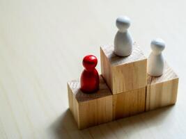 Red figure on podium among white figures concept of competition minimalist close-up view achievement photo