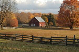 Red barn stands in autumn field with split rail fence photo