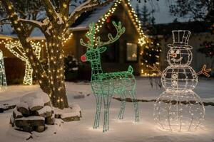 Glowing christmas decorations illuminating snowy front yard at night photo