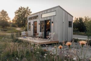 Modern tiny house with terrace in blooming meadow at sunset photo