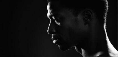 A black man in silhouette against a dark background photo