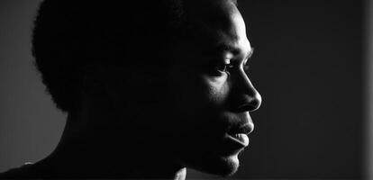 A black man in silhouette looking off to the side photo