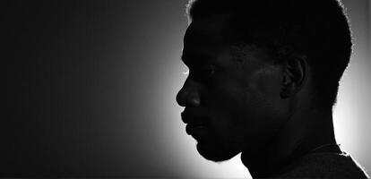 A black man in silhouette against a dark background photo