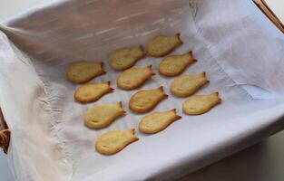 Baked Fish Shaped Crackers Arranged In Lines On White Napkin In Rattan Tray. Top View Of Domestic Cookies Detailed Stock Photo
