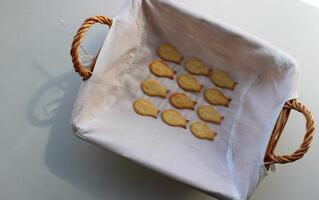 Domestic Fish Cookies In A Rows In Wicker Bread Basket On White Table photo