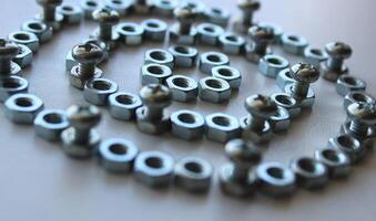 Concentrically arranged iron color nuts with bolts inserted into them reminiscent of part of a mechanism photo