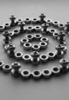 Grayscale Image Of Mechanical Pattern Part Made With Same Metal Nuts And Screwed Cross Head Bolts. Vertical Stock Photo For Mechanism Illustration