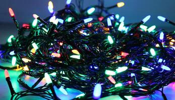 Twisted garland wires with LED bulbs shines into darkness isolated on white panoramic image. Holiday illumination and decoration stock photo