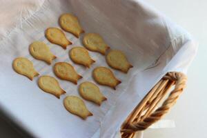 Rattan baking basket with straight lines of fish crackers on a clean cloth inside it photo