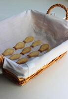 A straw bread tray lined with a white napkin and freshly baked crackers in a fish form. Homemade baking vertical stock photo