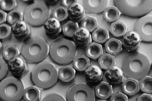 Black and white image of thread bolts injected in fixing nuts between flat washers. Macro shot stock photo for hardware products illustration