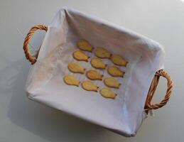 Salted cookies in a fish shape on a white towel in handmade weaved baking box photo