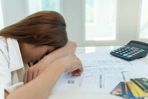 Stressed and headache asian woman with large bills or invoices no money to pay to expenses and credit card debt. shortage, Financial problems, mortgage, loan, bankruptcy, bankrupt, poor, empty wallet photo