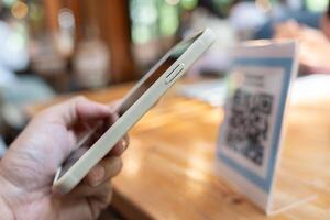 Woman use smartphone to scan QR code to pay in cafe restaurant with a digital payment without cash. Choose menu and order accumulate discount. E wallet, technology, pay online, credit card, bank app. photo