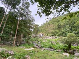 A waterfall in the jungle with rocks and trees photo