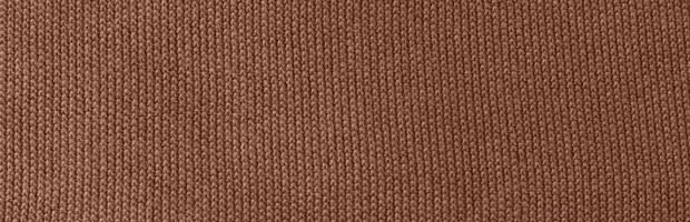 Texture of smooth knitted sweater with pattern. Handmade knitting wool or cotton fabric texture. Background of Large knit pattern with knitting needles or crochet. Mocha Mousse colour of 2025 year photo