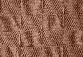 Texture of smooth knitted sweater with pattern. Handmade knitting wool or cotton fabric texture. Background of Large knit pattern with knitting needles or crochet. Mocha Mousse colour of 2025 year photo
