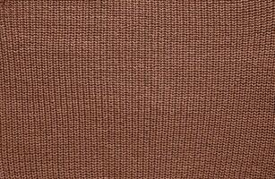 Texture of smooth knitted sweater with pattern. Handmade knitting wool or cotton fabric texture. Background of Large knit pattern with knitting needles or crochet. Mocha Mousse colour of 2025 year photo