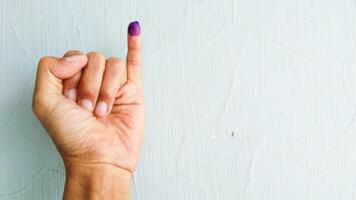 Hand with purple ink on the little finger, as a sign of having voted in the general election in Indonesia with isolated white background photo