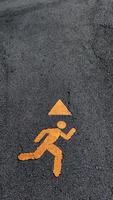 Safety sign indicating a running figure with a warning triangle. photo