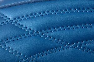 The macro texture of a blue leather sneaker with stitching. Part of the sports shoe is a close-up. photo