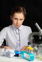 A boy scientist researcher with a microscope conducts experiments in the laboratory. The student studies biology and chemistry. Science and education. photo