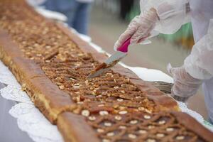 A chef's knife cuts yeast pies on an industrial tape. photo