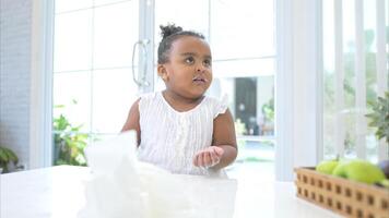 A tiny girl clean the table and floor after glass of milk spilled while drinking photo