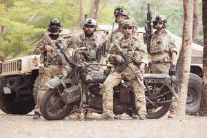 Portrait of soldiers in camouflage uniforms hold weapons in front of a military communication vehicle photo