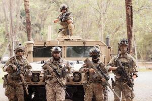 Portrait of soldiers in camouflage uniforms hold weapons in front of a military communication vehicle photo